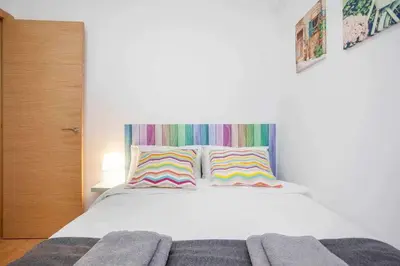 a bedroom with a white bed with two colorful pillows at Reus, Lovely Flat Close to Center in Valencia