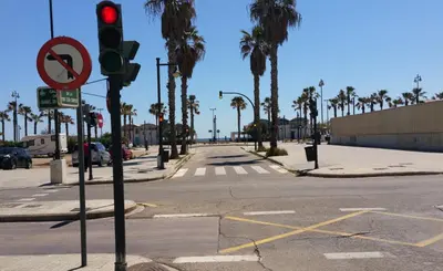 an empty street with a red traffic light and palm trees at Malvarossa apartment near beach in Valencia
