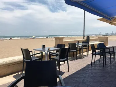 a row of tables and chairs on the beach at Malvarossa apartment near beach in Valencia