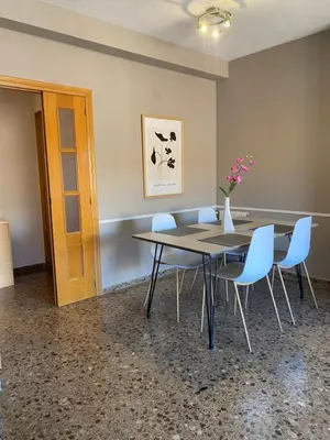 a table with blue chairs and a vase with flowers at Apartamento Ciencias y Playa in Valencia