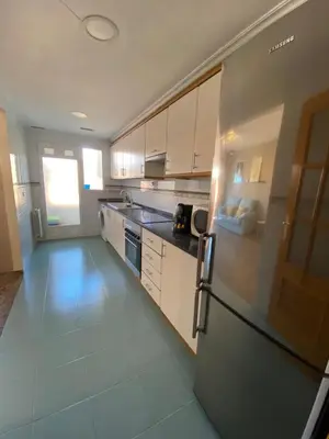 a kitchen with white cabinets and a stainless steel refrigerator at Apartamento Ciencias y Playa in Valencia