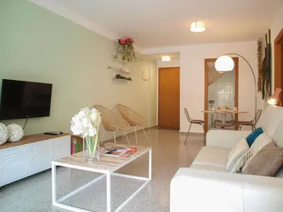 a living room with a white couch and a tv at ApartUP Patacona Beach II in Valencia