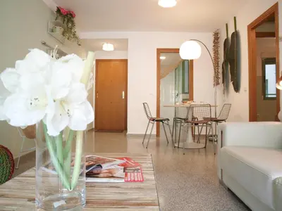 a living room with a vase of flowers on a table at ApartUP Patacona Beach II in Valencia