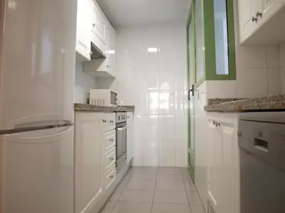 a white kitchen with white cabinets and white appliances at ApartUP Patacona Beach II in Valencia