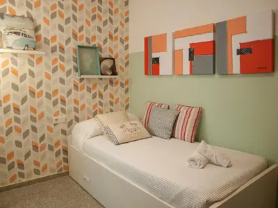 a small bed in a room with paintings on the wall at ApartUP Patacona Beach II in Valencia