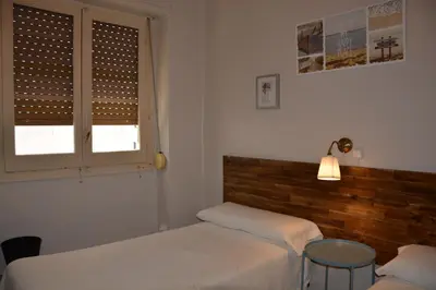 a bedroom with two beds and a table and a window at Pensión Moratin in Valencia