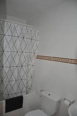 a white bathroom with a toilet and a sink at Pensión Moratin in Valencia