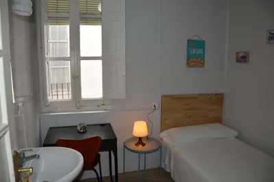 a bedroom with a bed and a sink and a desk at Pensión Moratin in Valencia