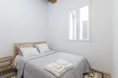 a white bedroom with a bed with two towels on it at Casa Nolla in Valencia