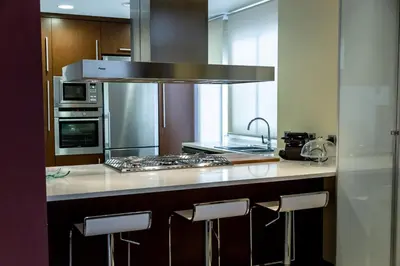 a kitchen with a stove and a counter with stools at Travel Habitat Ático Ciutat Vella. in Valencia