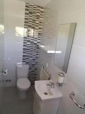 a white bathroom with a toilet and a sink at Pensíon Lucia in Casinos