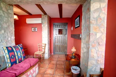 a living room with a couch and a red wall at Casa Rural Mirador del Salto in Chella