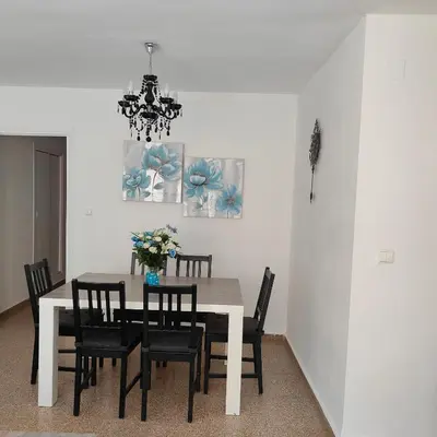 a dining room table with black chairs and a chandelier at Relaxed Space in the beach in Puerto de Sagunto