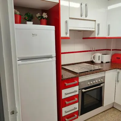 a kitchen with a white refrigerator and red cabinets at Relaxed Space in the beach in Puerto de Sagunto