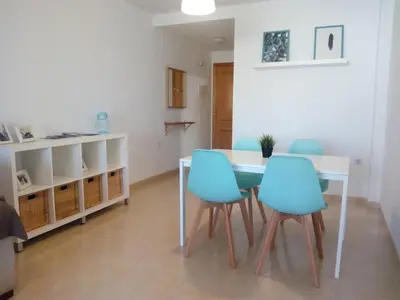 a dining room with a table and blue chairs at El apartamento de Marina en Moncofar playa in Moncófar