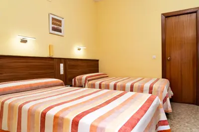 two beds in a hotel room with yellow walls at Hotel Borja in El Puig