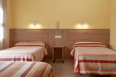 a room with two beds and a table at Hotel Borja in El Puig
