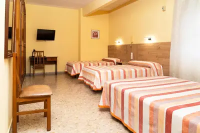 a row of four beds in a hotel room at Hotel Borja in El Puig