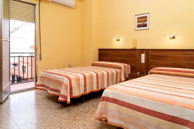 a hotel room with two beds and a balcony at Hotel Borja in El Puig