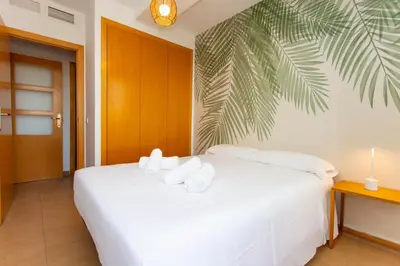 a white bed in a room with a palm leaf wall at 4-Seasons Penthouse Cullera in Cullera