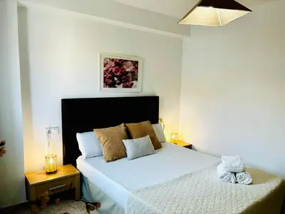 a bedroom with a white bed with a black headboard at Travel Habitat Jardines de Viveros in Valencia