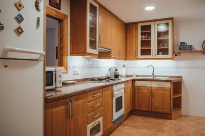a kitchen with wooden cabinets and a white refrigerator at Avinguda Mare Nostrum, 101 in Moncófar