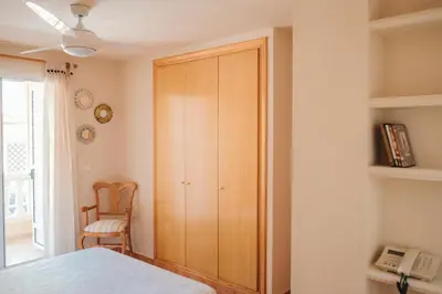 a bedroom with a wooden cabinet and a chair at Avinguda Mare Nostrum, 101 in Moncófar