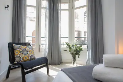 a bedroom with a chair and a large window at SingularStays Santa Clara in Valencia