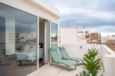 a balcony with two chairs and a bed on it at Teide Rooms in Puerto de Sagunto