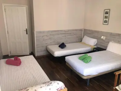 three beds in a small room with red and green towels at Mar & City Apartment in Valencia