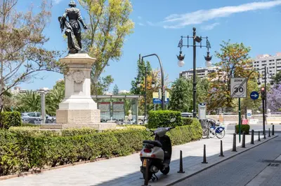 a scooter parked on a sidewalk next to a statue at My Loft 4 You Temple in Valencia