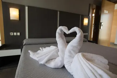 two swans made out of towels on a bed at El Chalet in Cullera