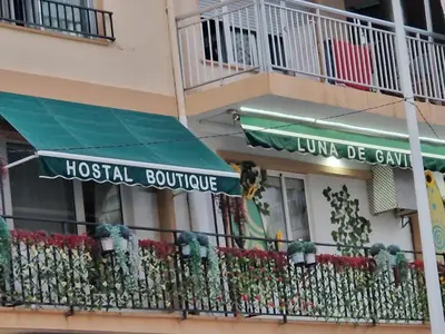 a hospital building with awnings and flowers on a balcony at Hostal Boutique Luna de Gavín in Cullera