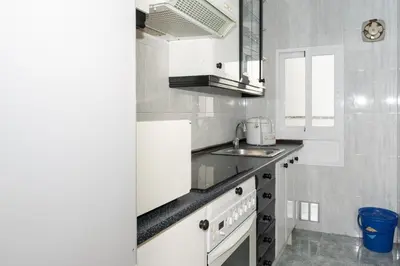 a white kitchen with a sink and a stove at Mar y Montaña, 2º-18 in Cullera