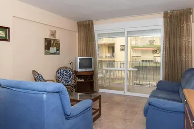 a living room with two blue chairs and a television at Mar y Montaña, 2º-18 in Cullera