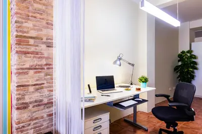 an office with a brick wall and a desk with a computer at Fun&Happy VLC Center in Valencia
