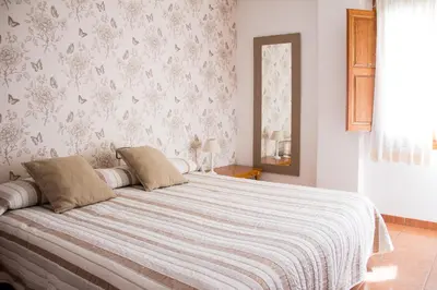 a bedroom with a large bed with a white blanket at Hostal El Pozo in Chulilla