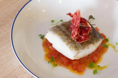 a plate of food with a piece of fish on top of tomato sauce at Hostal El Pozo in Chulilla