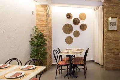 a dining room with a table and chairs and a plant at Hostal El Pozo in Chulilla