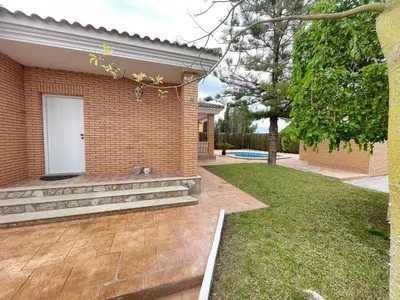 a brick house with a white door and a yard at Casa Maica in Lliria