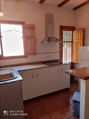 a kitchen with white cabinets and a sink and a window at La Rueda Apartamentos Rurales in Chulilla