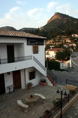 a building with a table in front of it with a mountain at La Rueda Apartamentos Rurales in Chulilla
