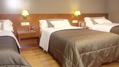 a hotel room with two beds and two lamps at Hotel Avenida in Requena