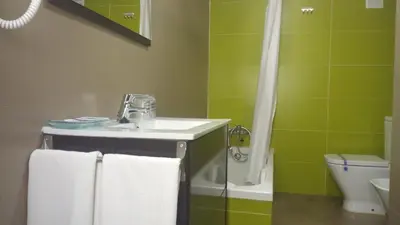 a bathroom with a sink and a shower with towels at Hotel Avenida in Requena