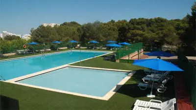 a large swimming pool with umbrellas and chairs at Camping Santamarta in Cullera