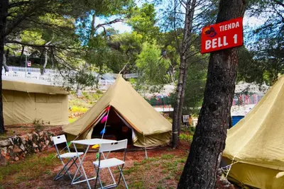 a tent with chairs and a sign on a tree at Camping Santamarta in Cullera