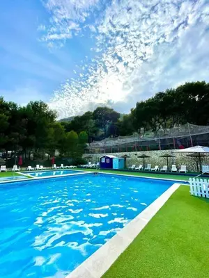 a large swimming pool with blue water and white chairs at Camping Santamarta in Cullera