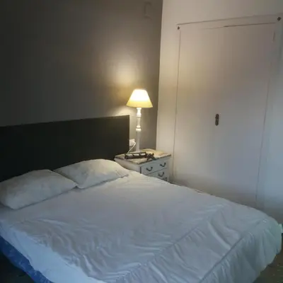 a bedroom with a white bed with a lamp and a door at Casa De La Luz in Valencia