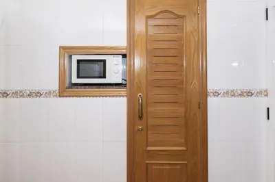 a wooden door with a microwave in a bathroom at Mari Carmen, 2º-8 in Cullera