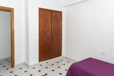 a bedroom with a wooden door and a purple bed at La Ponderosa, 4º-21 in Cullera
